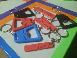 Image shows a collection of 3D-printed bottle openers and whistles that say "BusKill"